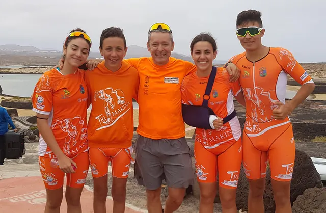 Fran Delgado con cuatro jóvenes deportistas del equipo, todos con la equipación naranja