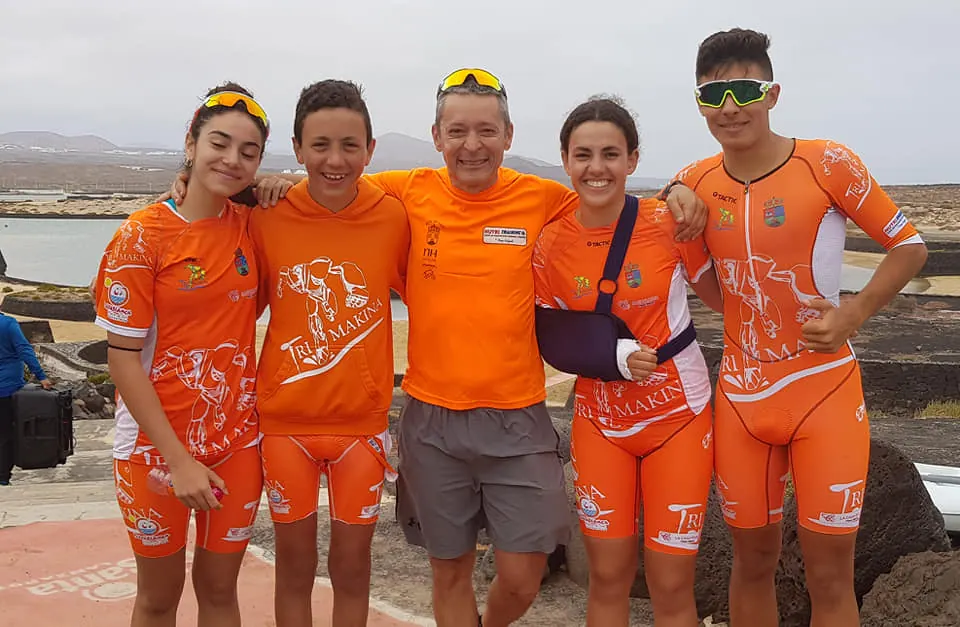Fran Delgado con cuatro jóvenes deportistas del equipo, todos con la equipación naranja