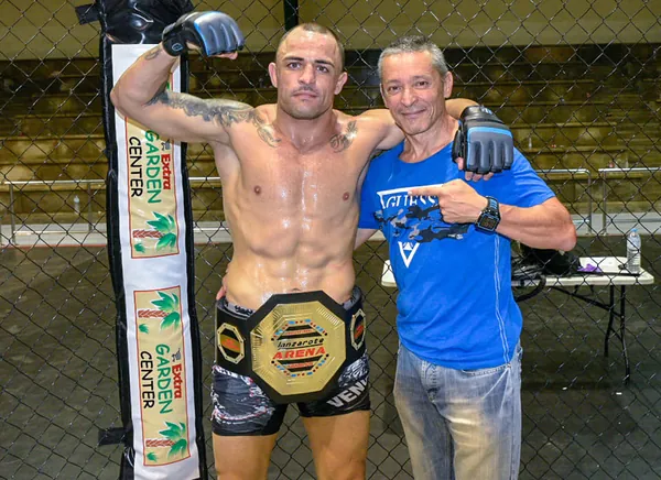 Fran Delgado con un luchador que muestra su cinturón de campeón