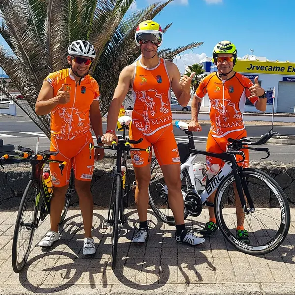Tres triatletas del equipo Trimakina con sus bicicletas junto al mar