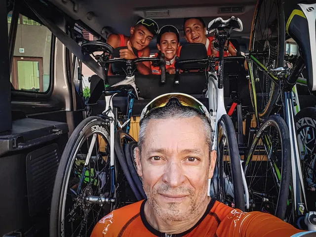 Fran Delgado haciéndose un selfi en la furgoneta, entre bicicletas, con tres jóvenes del equipo detrás