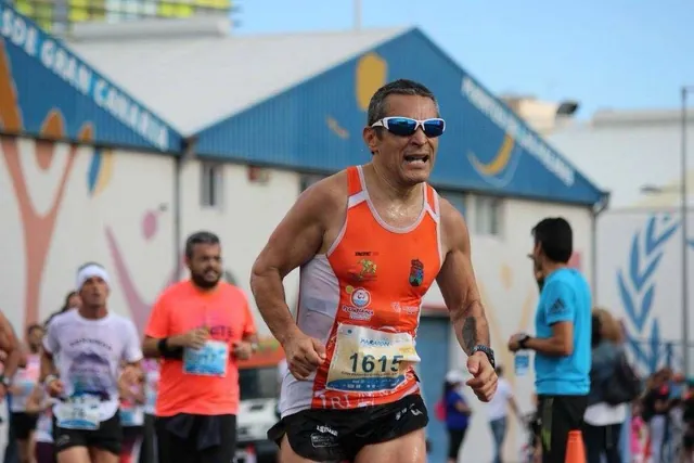 Fran Delgado corriendo una maratón con la camiseta naranja del equipo