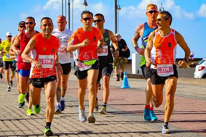 Corredores del equipo con camisetas naranjas en el paseo marítimo durante una carrera