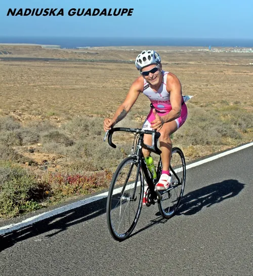 Ciclista con maillot rosa por una carretera de Lanzarote junto al mar