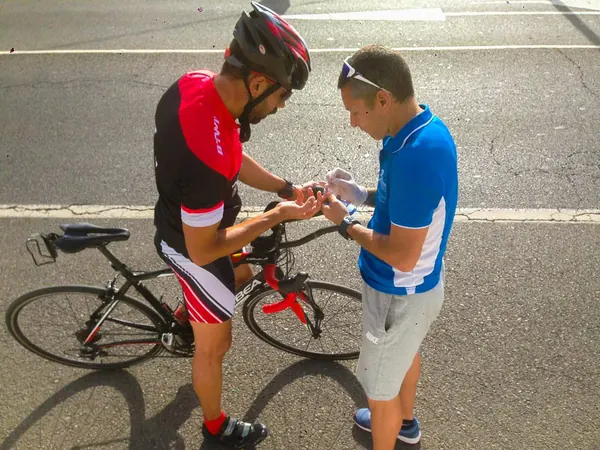 Fran Delgado tomando una muestra de sangre del dedo a un ciclista para medir su lactato